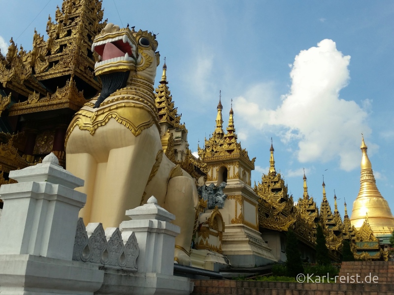 Der Haupteingang mit den dahinter liegenden, überdachten Treppen und der Shwedagon Pagode im Hintergrund.