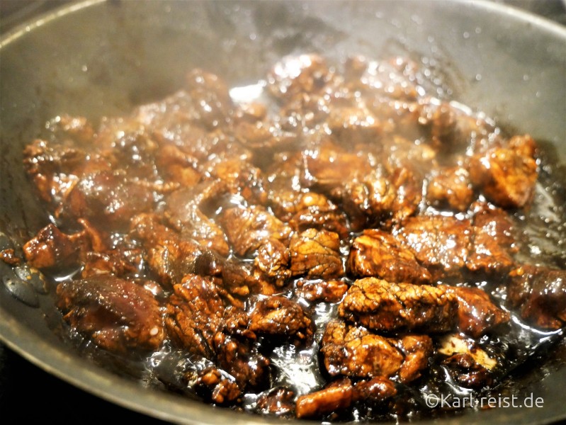 Mariniertes Fleisch in der Pfanne mit Öl und Knoblauch